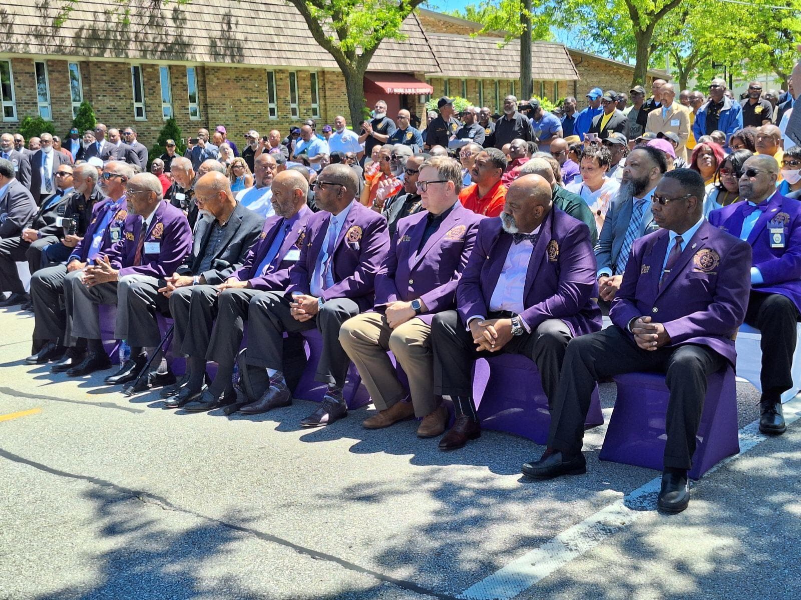 USC members seated in purple blazers at an outdoor ceremony